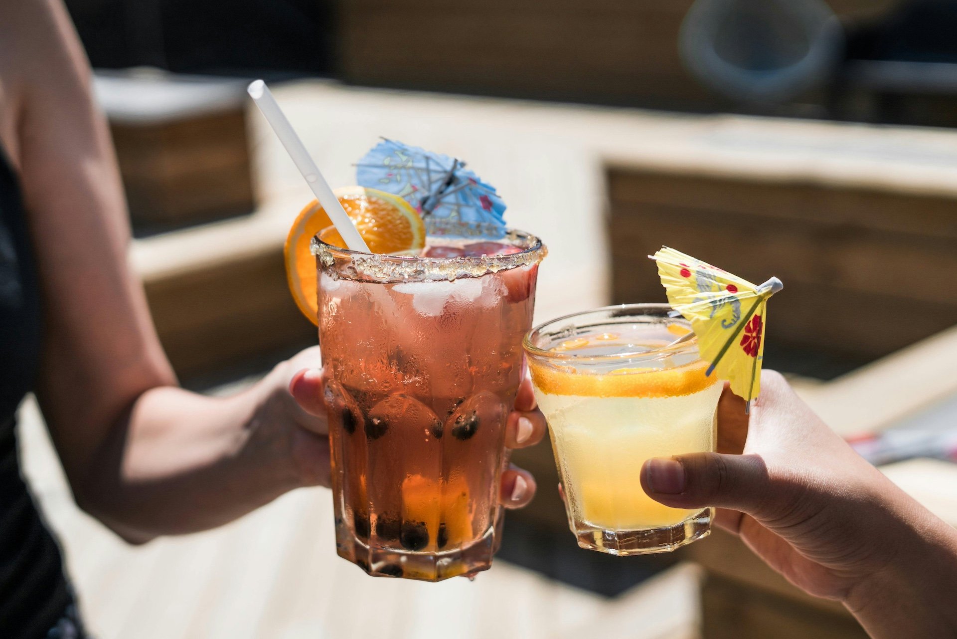 Two people clinking colorful cocktails together