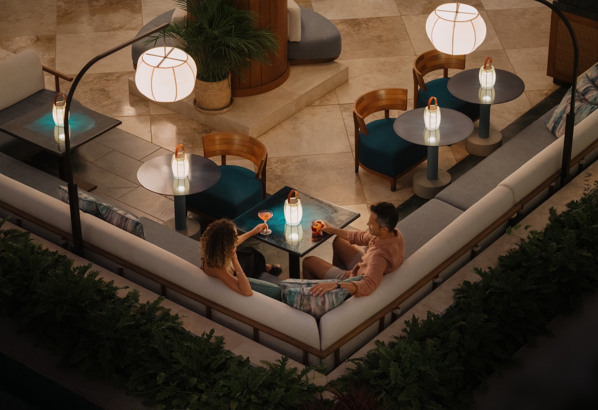 A couple sitting in the corner of a patio booth illuminated by lanterns