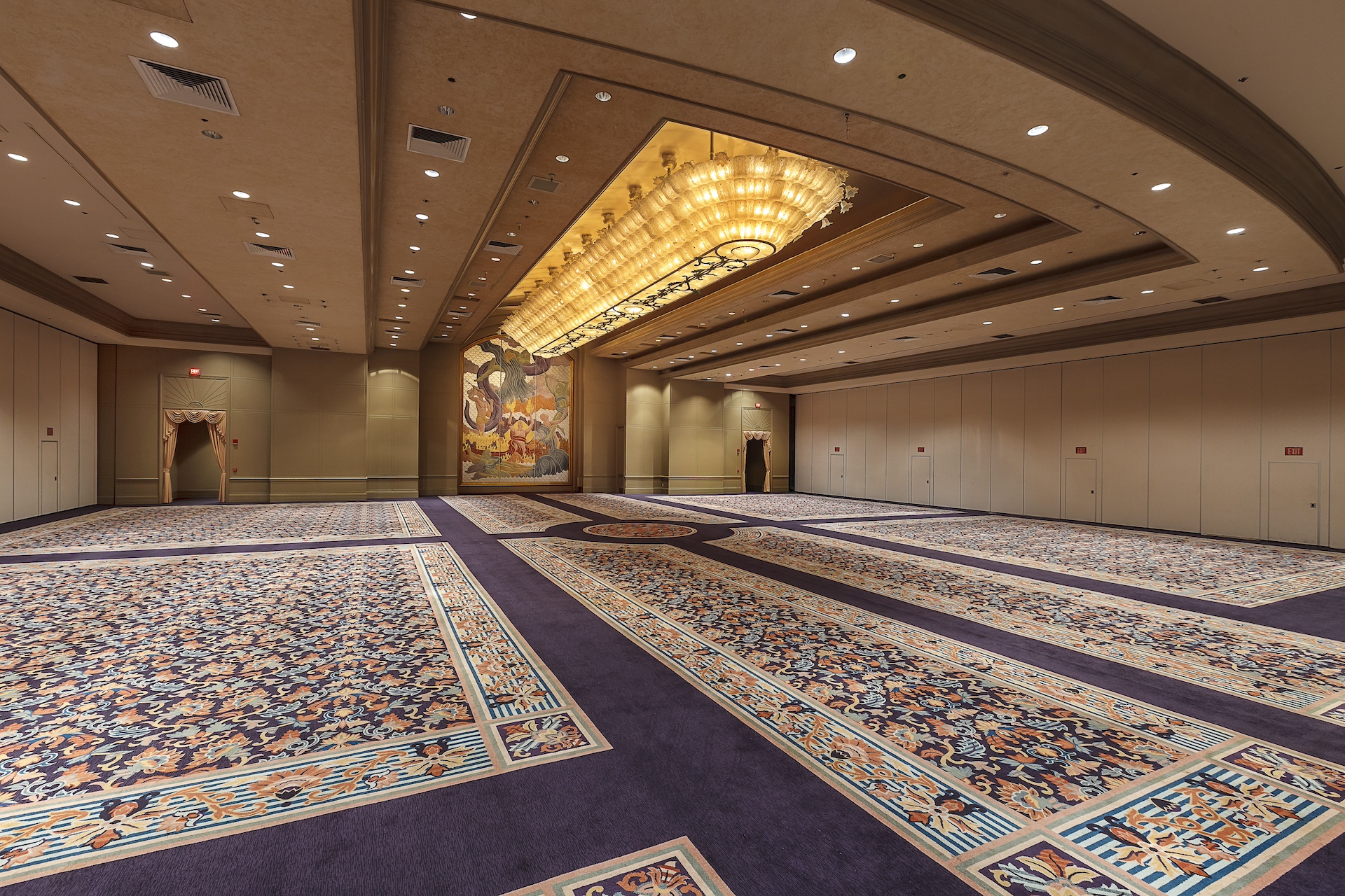 A large empty ballroom with an elaborate carpet