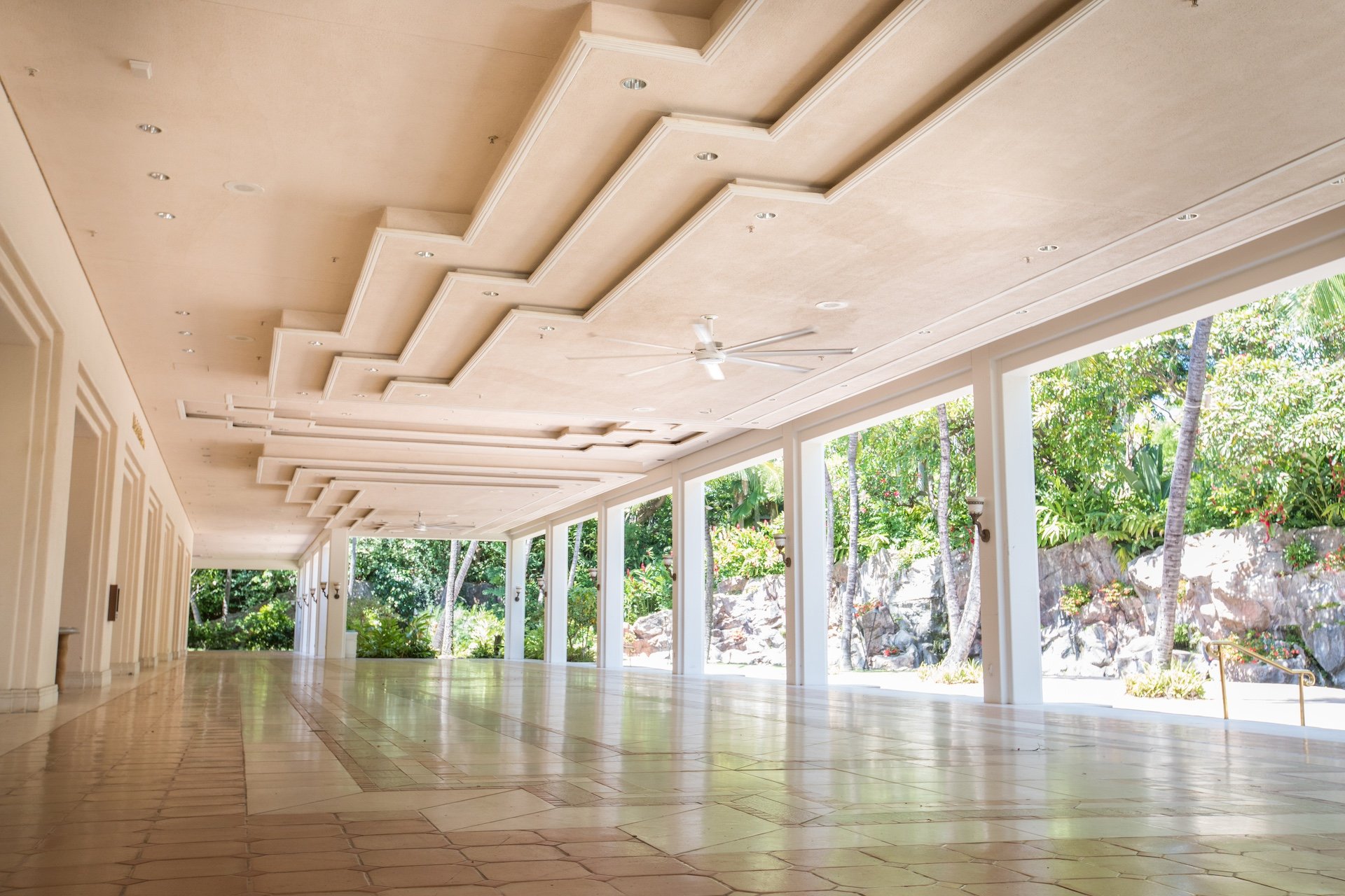 A courtyard with a columned overhang next to a garden