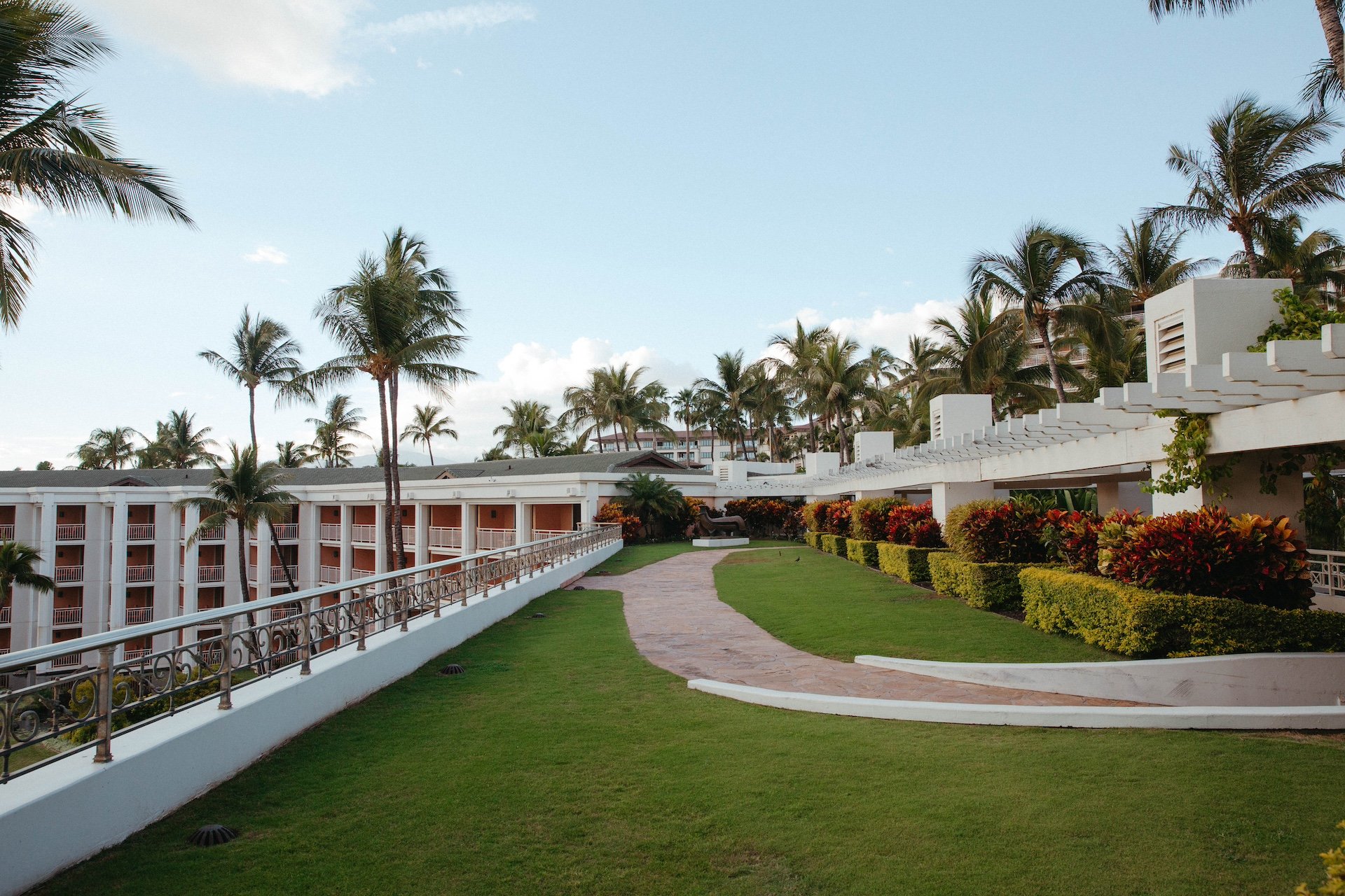 winding path through a lush green terrace on the upper level of a resort