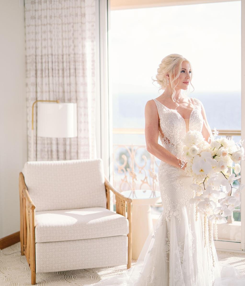 A beautiful bride wearing a white dress and holding a bouquet of white roses in a hotel room