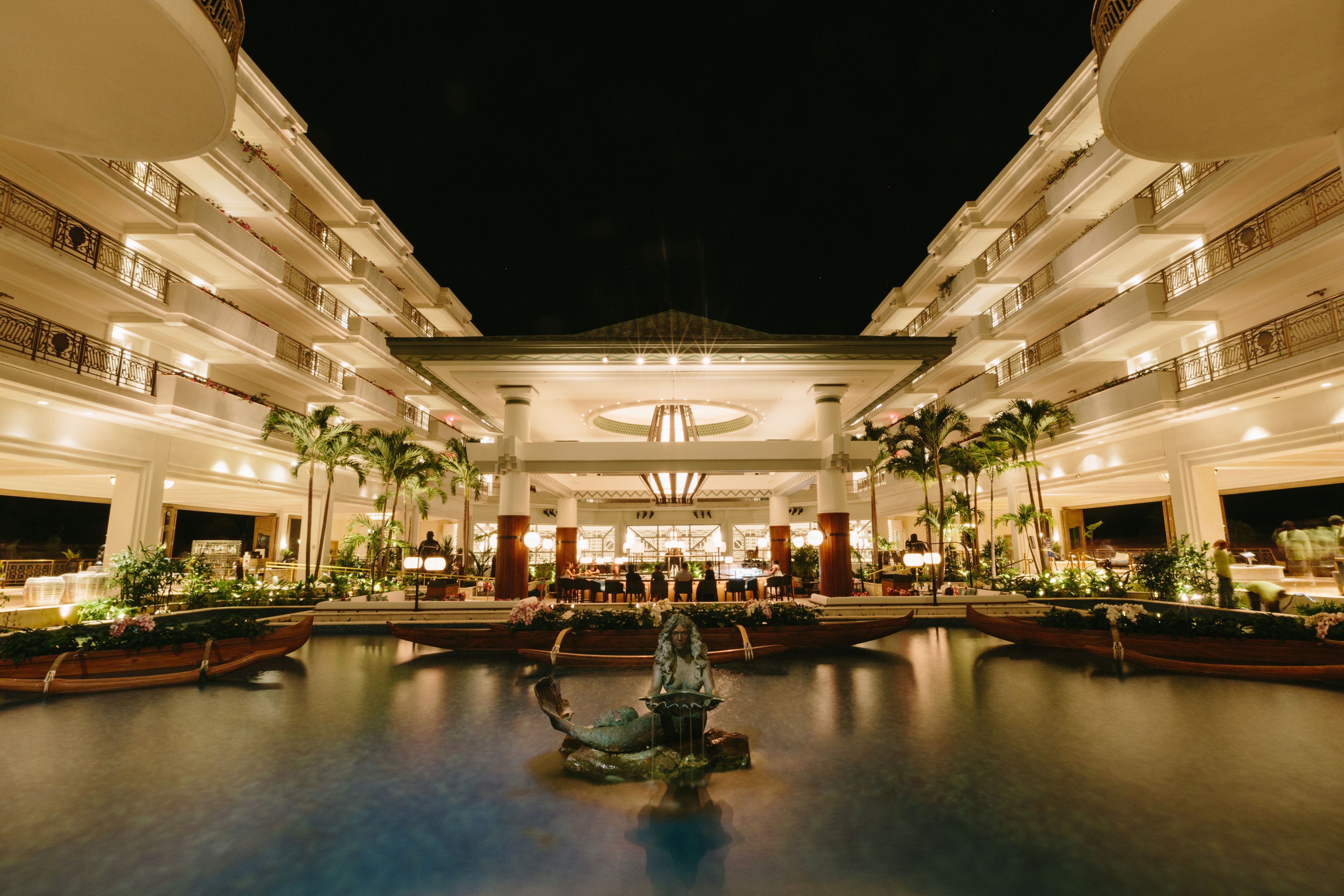 The exterior of a restaurant with a pond feature in the foreground, at night