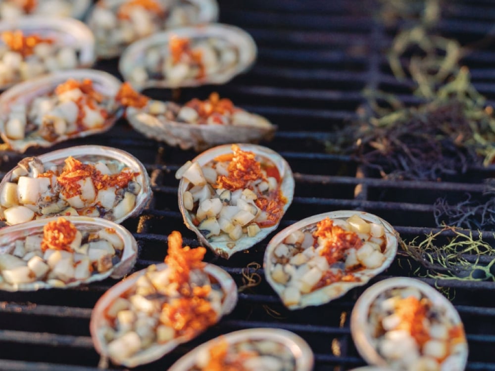 A tray of oysters topped with vegetables