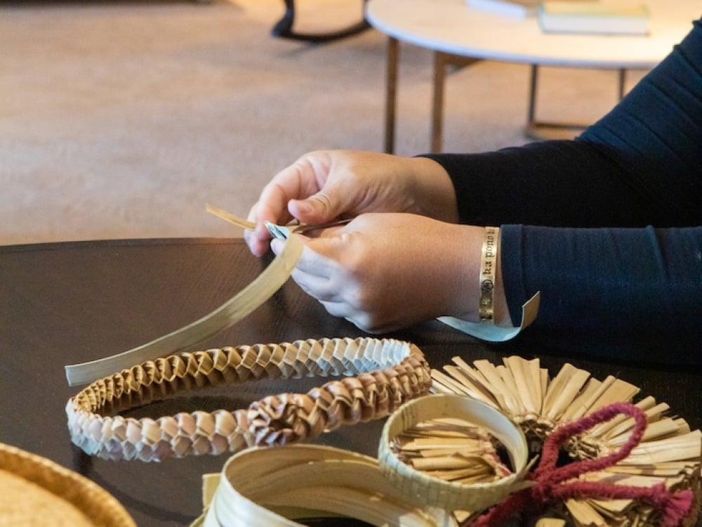 A person weaving a Lauhala Bracelet