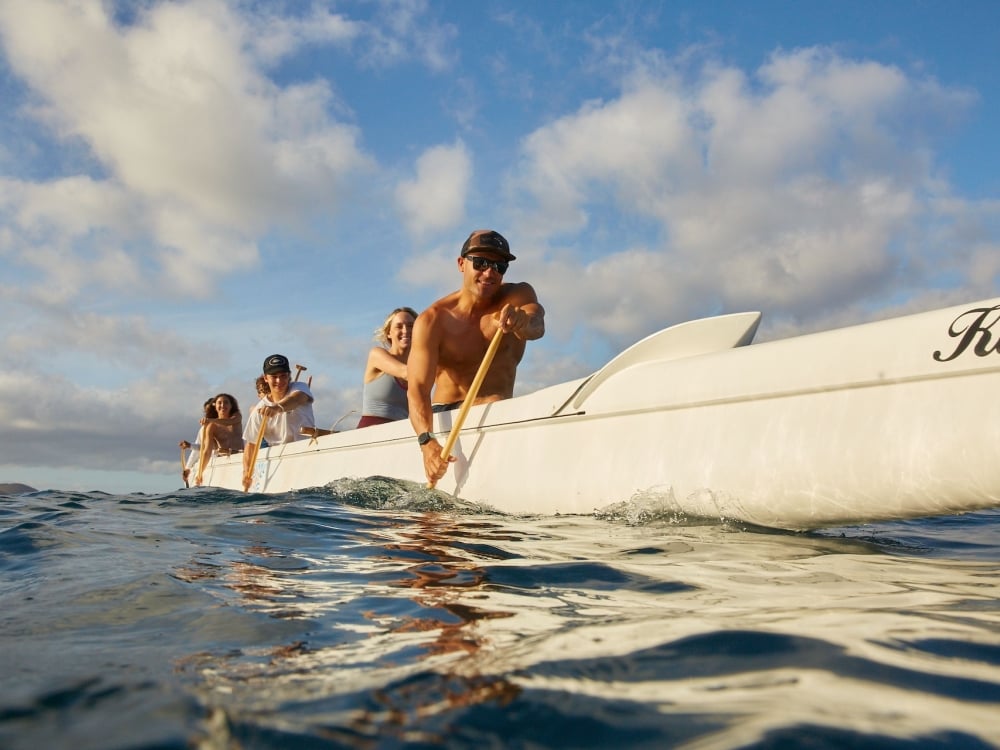 A group paddling a large white boat