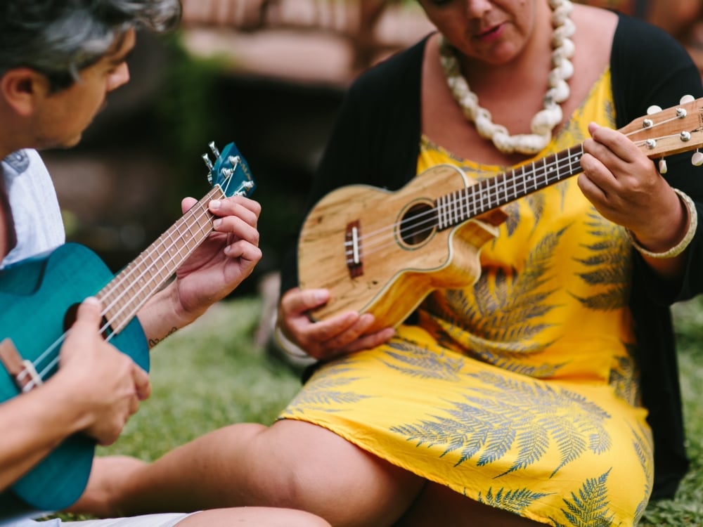 A woman demonstrating to another woman fingerings on a ukelele