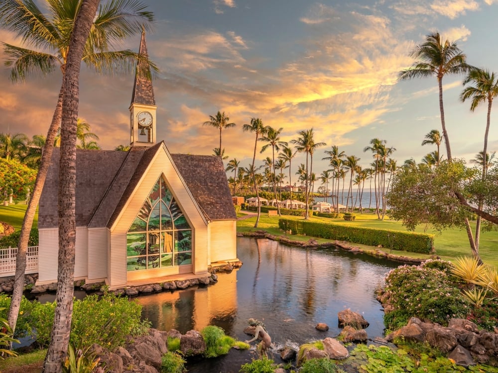 A small chapel in a garden lined with palm trees