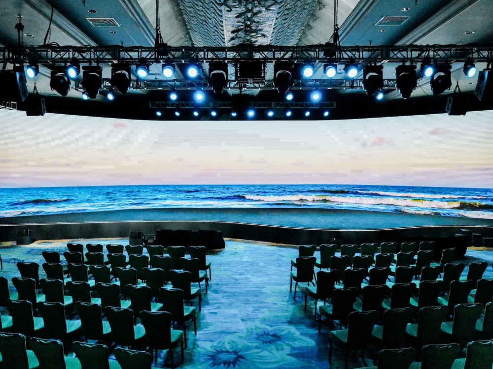 A large ampitheatre with stage lighting looking directly out on the ocean from a bay window