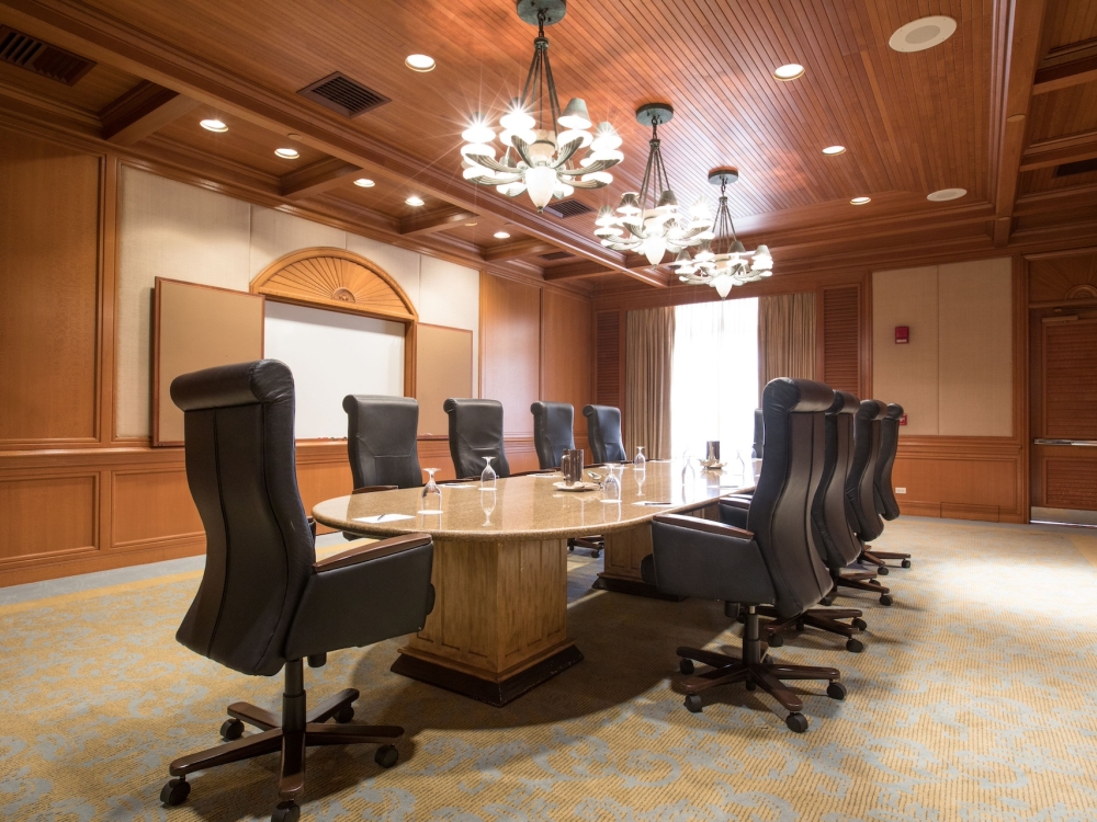 A boardroom with black leather chairs around an oval table