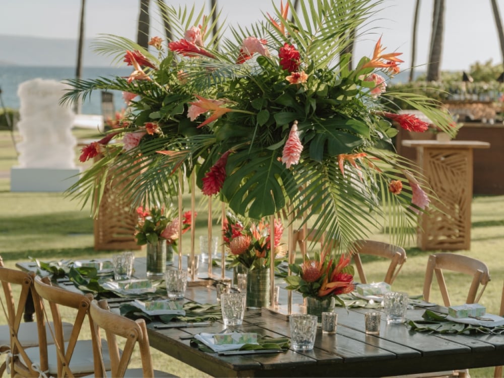A tropical floral arrangement on a table at an outdoor wedding