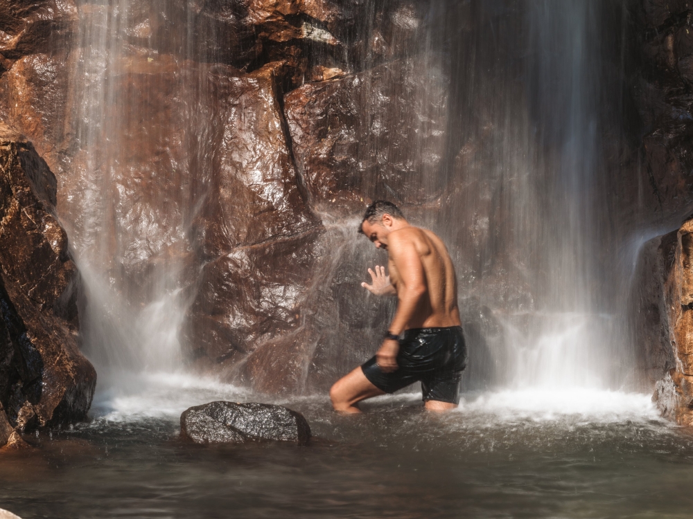 A man standing underneath a waterfall