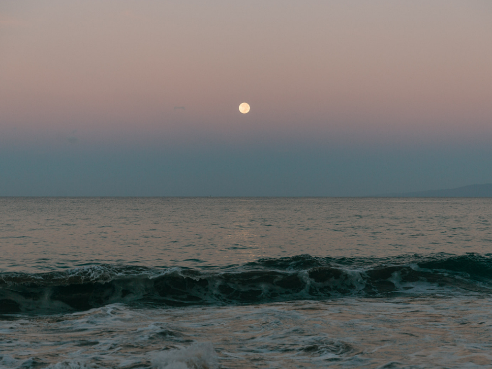 An image of the ocean landscape with the sun setting in the background 