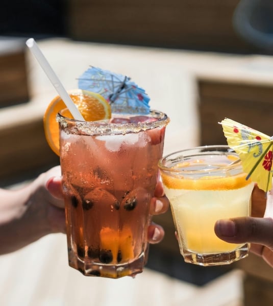 Two people clinking colorful cocktails together