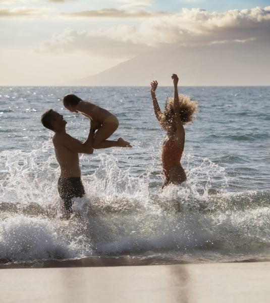 A group of people frolic in the shallow waters of a beach