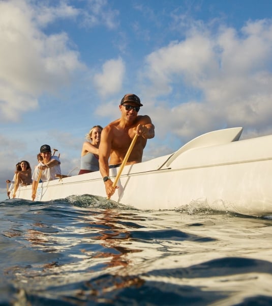 A group paddling a large white boat