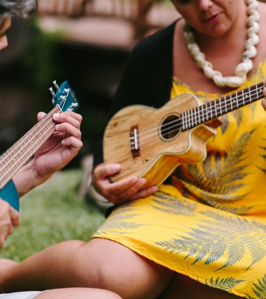 A woman demonstrating to another woman fingerings on a ukelele