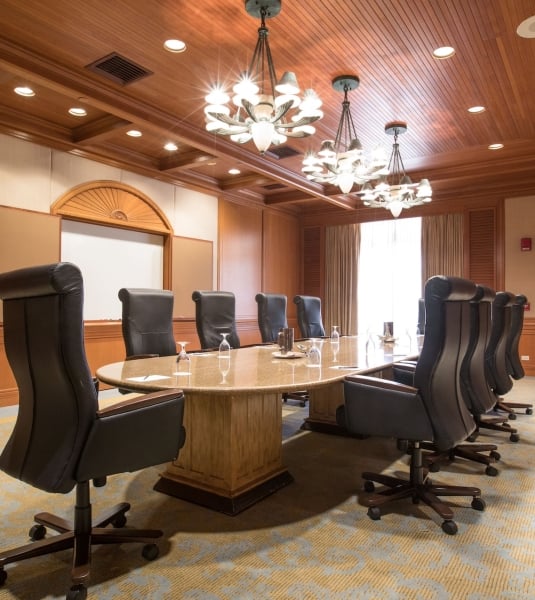 A boardroom with black leather chairs around an oval table