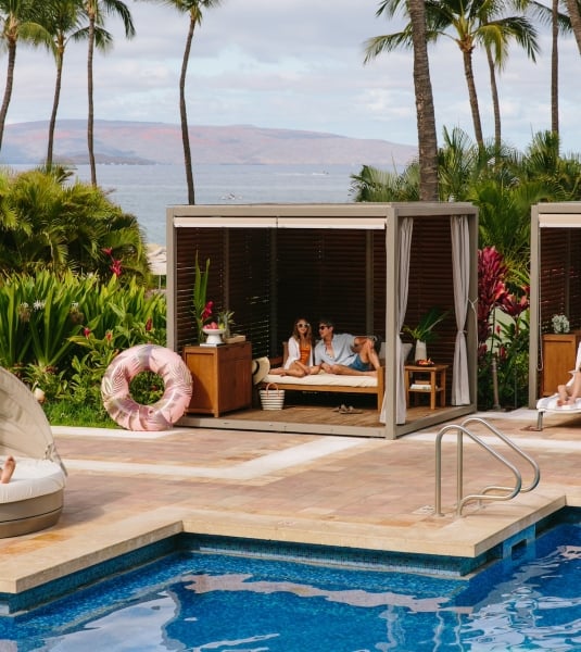 People relaxing in poolside cabanas