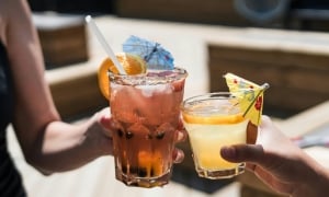 Two people clinking colorful cocktails together