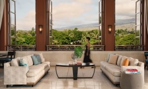 A woman traverses a lobby with grand bay windows looking out onto a green landscape