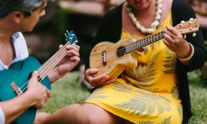 A woman demonstrating to another woman fingerings on a ukelele