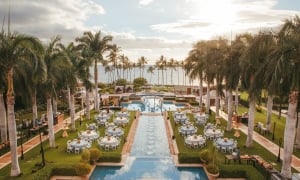 A poolside garden in view of the ocean, set up with banquet tables