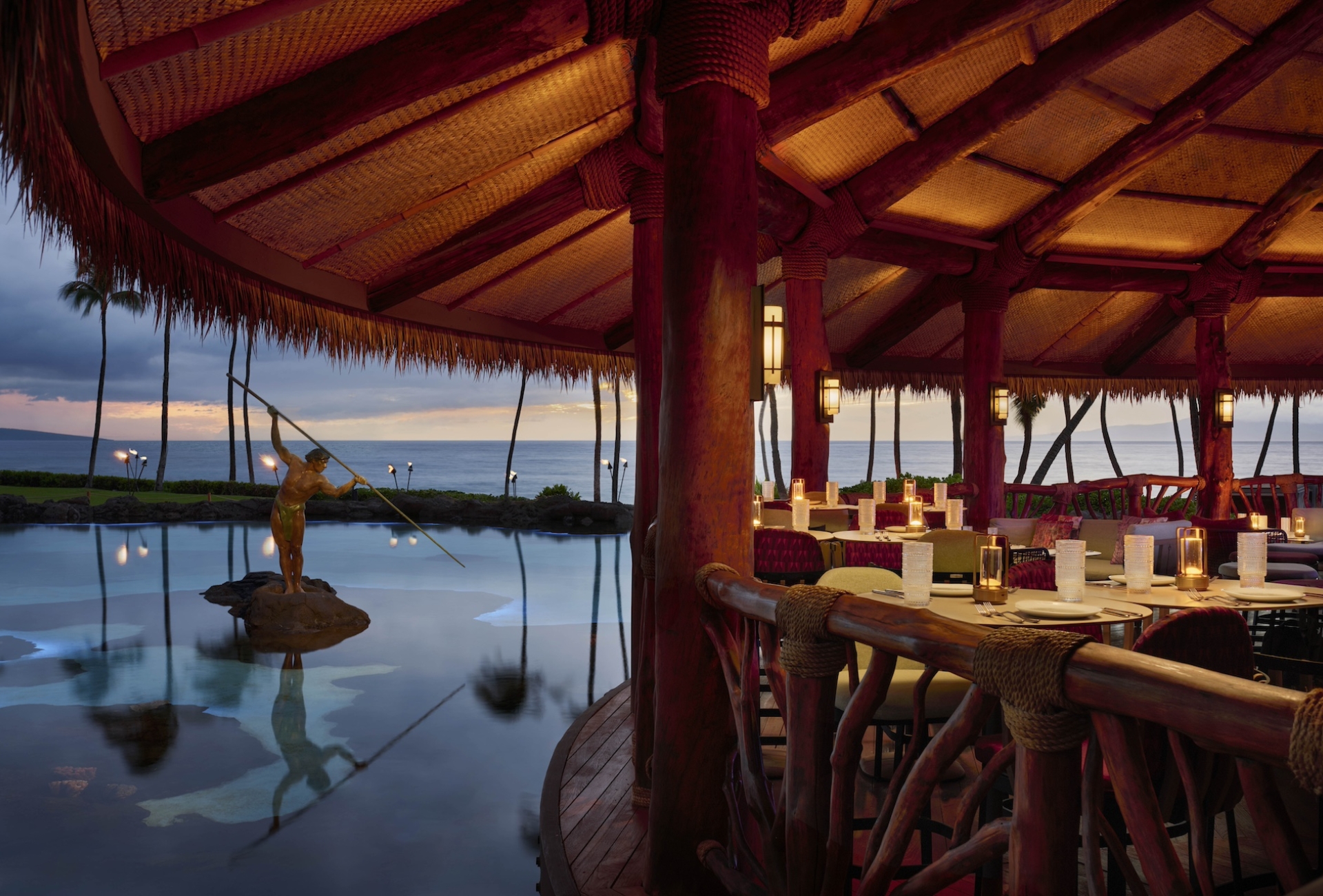 An oceanside patio, next to a statue, at dusk