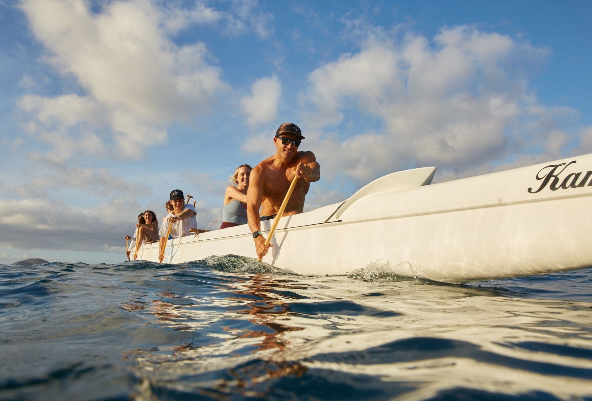 A group paddling a large white boat