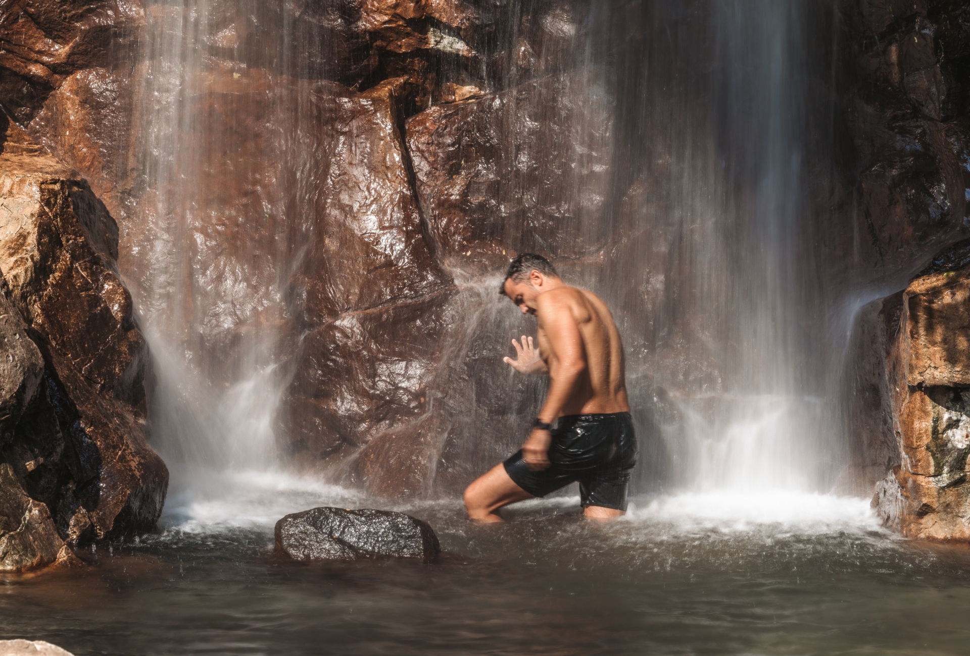 A man standing underneath a waterfall