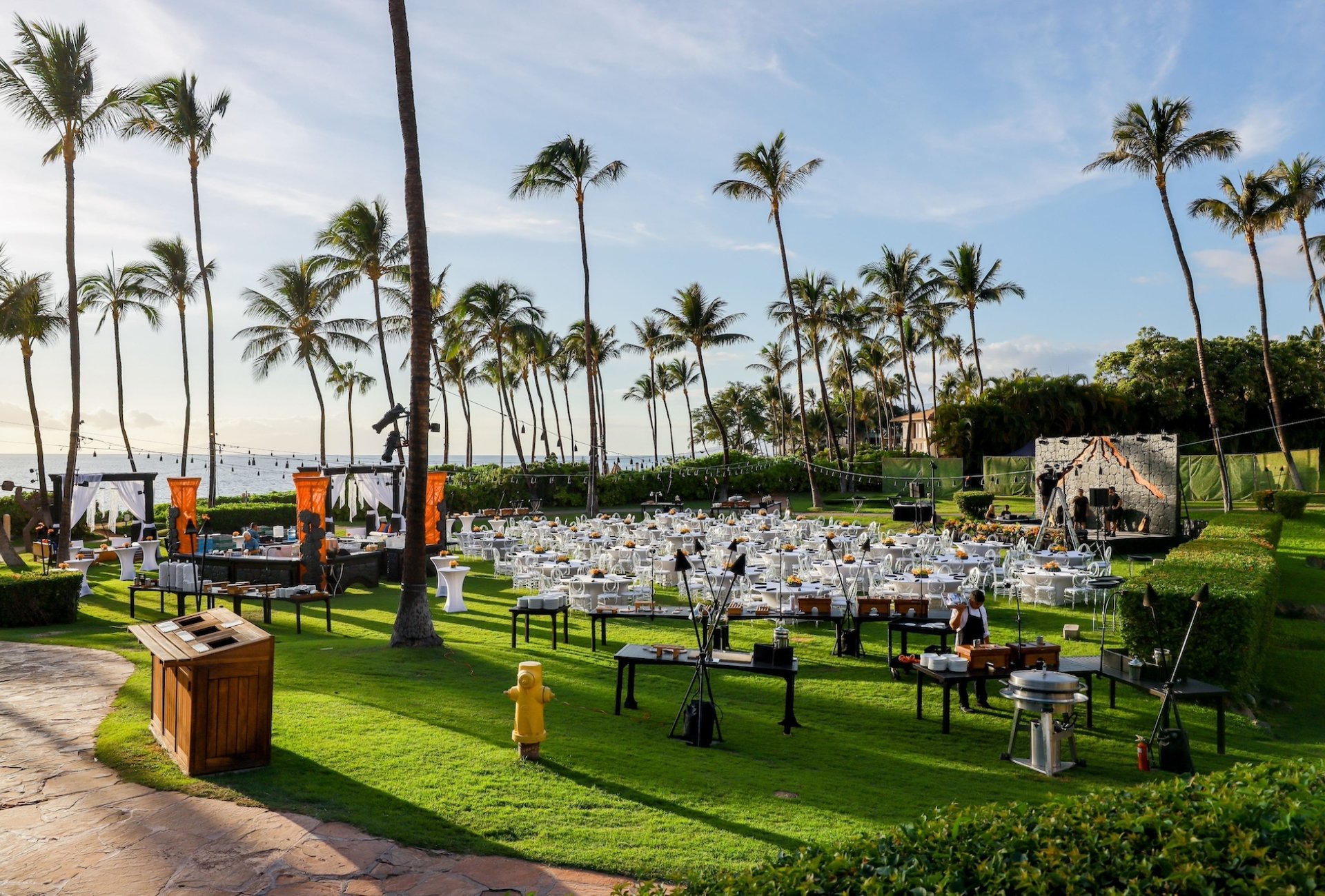 A lawn lined with palm trees, set up with tables for an outdoor dinner