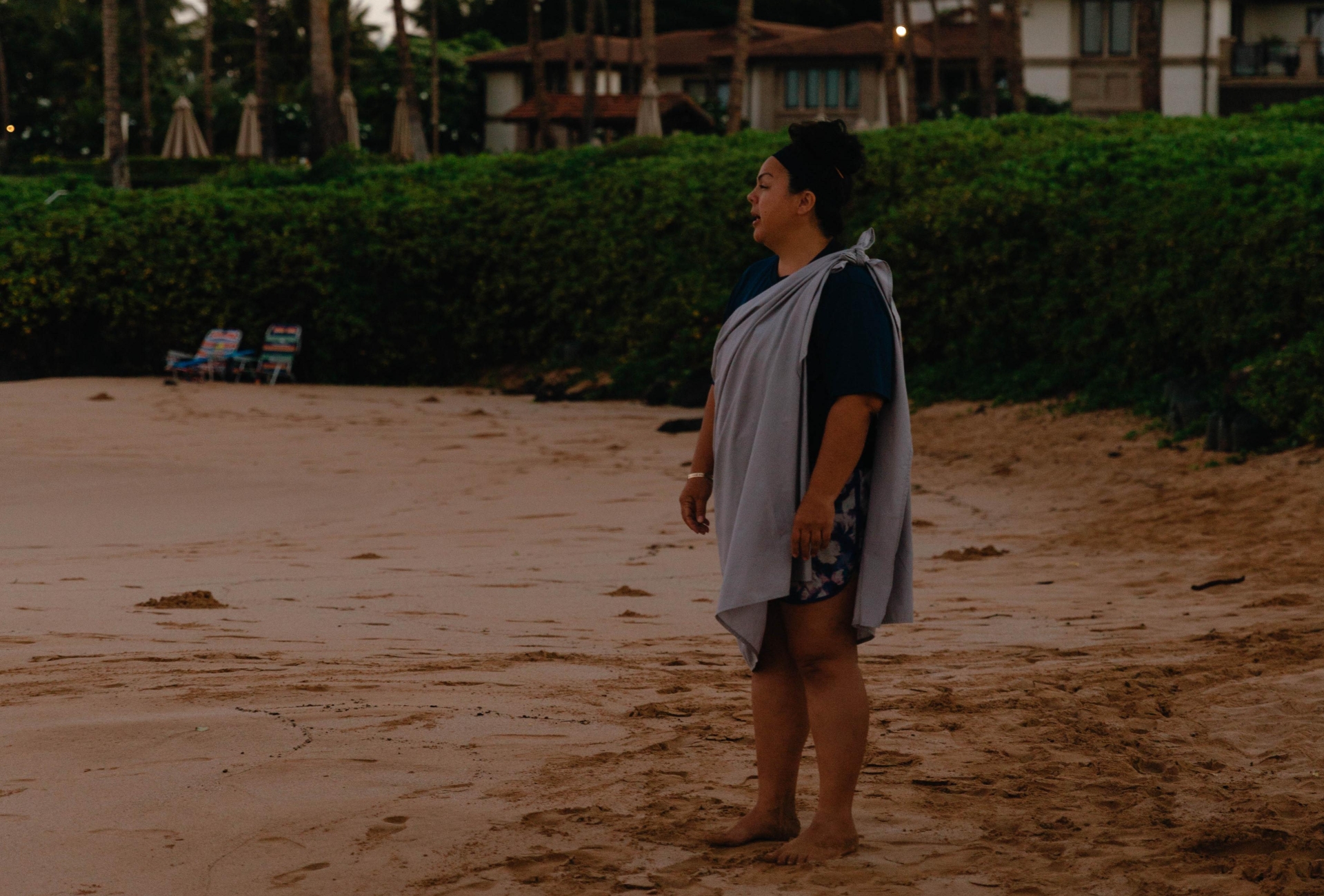 A woman standing on the beach reciting the E Ala E chant 