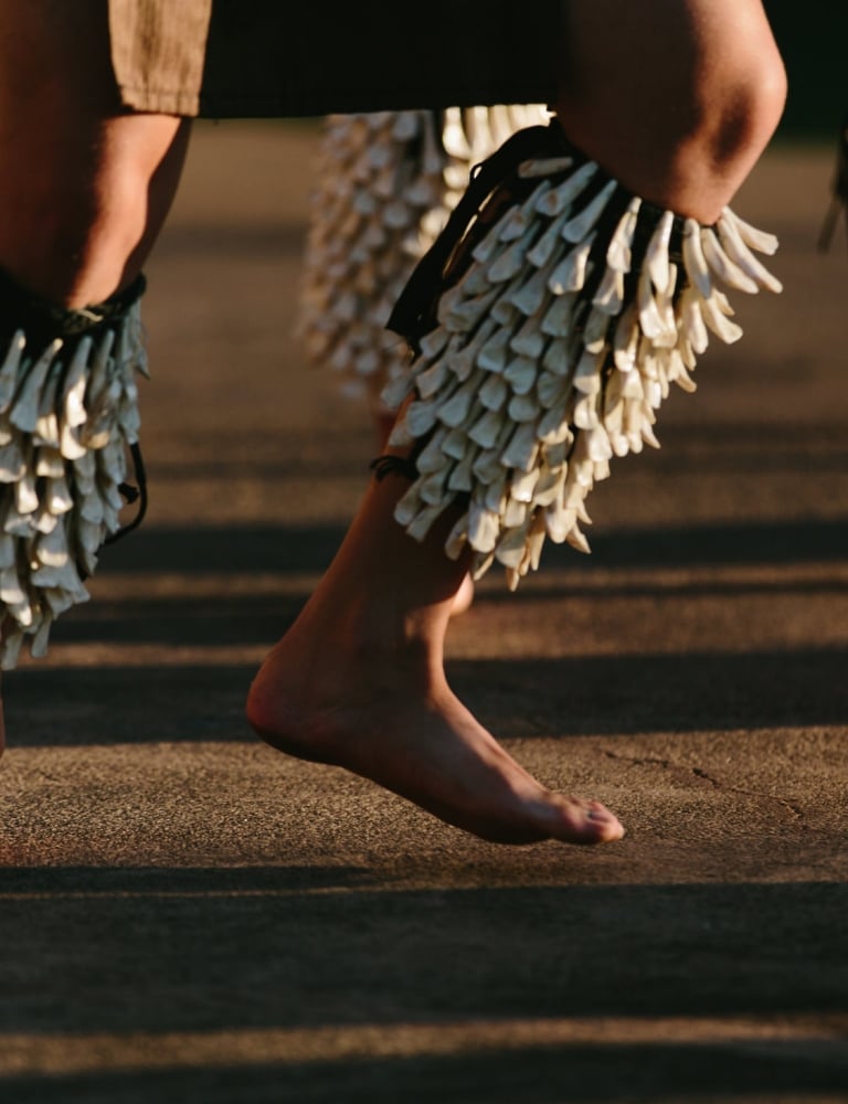 two sets of legs hop while wearing shells and dancing the luau